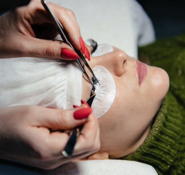 eyelash-extension-process-closeup-portrait-young-girl-woman-with-long-thick-eyelashes-eyes-closed-hand-cosmetologist-adding-more-eyelashes-her