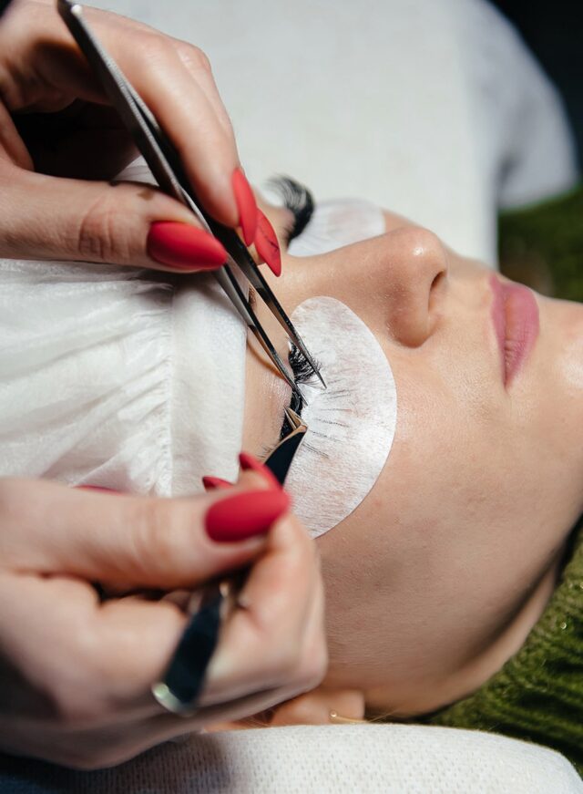 eyelash-extension-process-closeup-portrait-young-girl-woman-with-long-thick-eyelashes-eyes-closed-hand-cosmetologist-adding-more-eyelashes-her